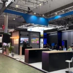 The Colorlight booth at ISE 2025 in Barcelona, showcasing state-of-the-art LED video processors and media server solutions. The booth features a sleek, modern design with vibrant lighting and multiple high-resolution screens demonstrating Colorlight's cutting-edge technology. Prominent signage displays the Colorlight logo and the slogan "Creative Video · Infinite Future," reflecting the brand's vision. The setup includes interactive areas for product demonstrations and tables for in-depth discussions with attendees. The booth's lively atmosphere and professional layout underline Colorlight's position as a leader in innovative video processing solutions.
