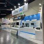 The MSI booth at Embedded World 2025 in Nuremberg, showcasing advanced solutions in artificial intelligence and Internet of Things (AIoT). The booth is brightly lit and features modern design elements, prominently displaying MSI's branding and product highlights. Key innovations such as "Edge AI for PCB AOI" and "Remote Control Management" are showcased through interactive screens and demonstrations. Multiple devices and informational panels emphasize MSI's commitment to leading-edge AIoT technologies. The setup also includes seating areas and counters for discussions with attendees, reflecting a professional and welcoming atmosphere. This vibrant booth demonstrates MSI's dedication to driving innovation in AI and IoT sectors.